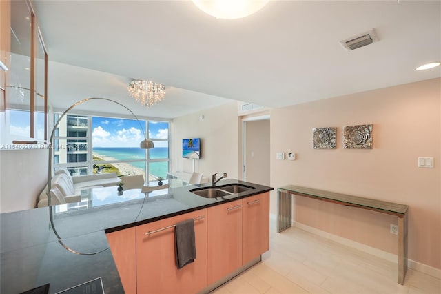 kitchen featuring a notable chandelier, light hardwood / wood-style floors, sink, and a water view