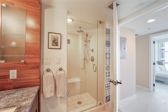 bathroom featuring tile flooring, a shower with shower door, and vanity