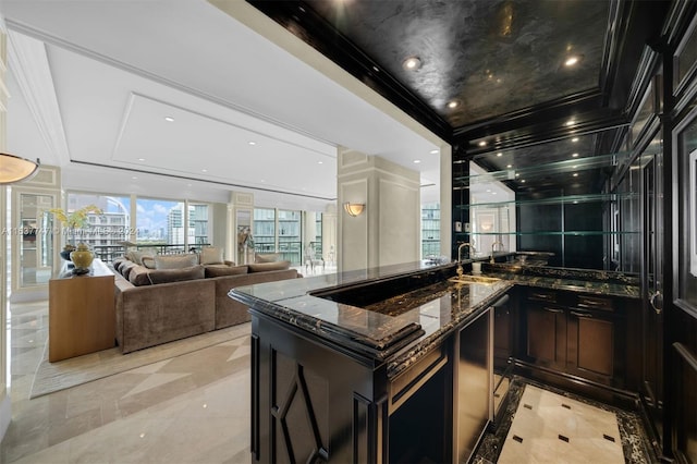 kitchen featuring a kitchen island with sink, light tile floors, and dark stone countertops