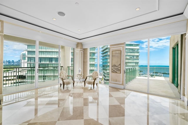 sitting room with light tile floors, expansive windows, a raised ceiling, and a water view