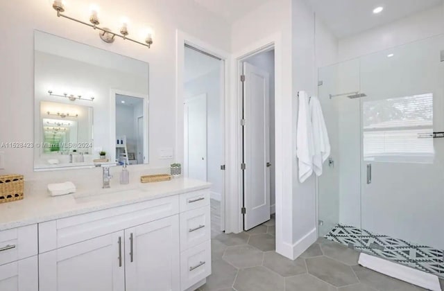 bathroom with a shower with shower door, vanity with extensive cabinet space, and tile flooring