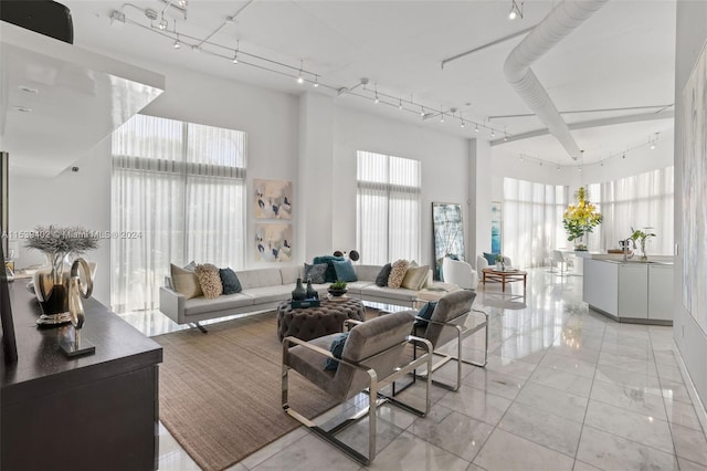 tiled living room featuring rail lighting and a towering ceiling