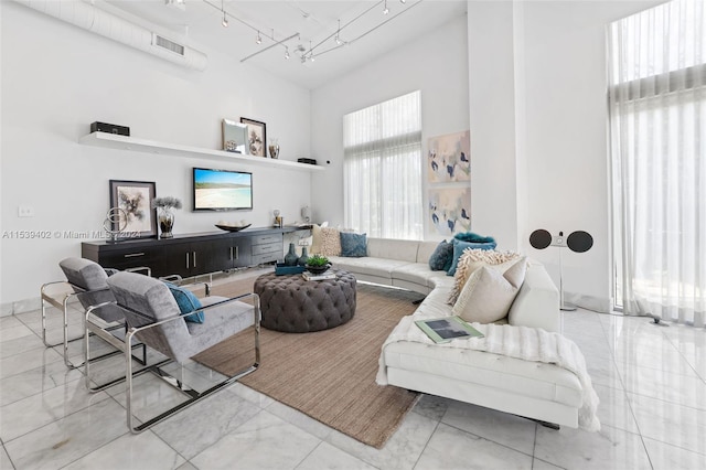 living room featuring light tile floors, rail lighting, and a towering ceiling