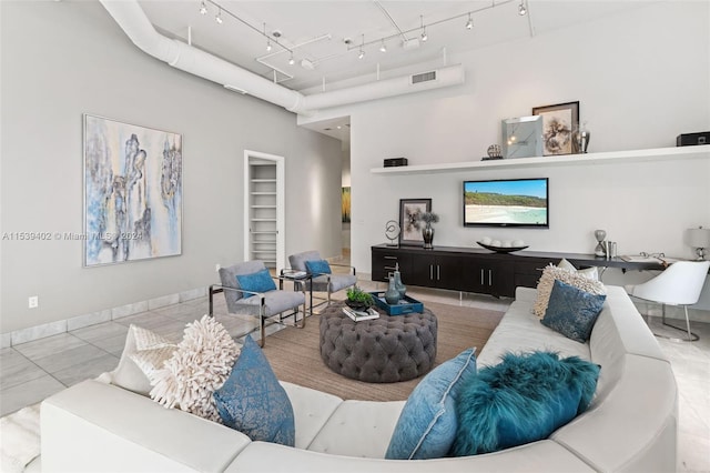 tiled living room featuring a high ceiling and rail lighting