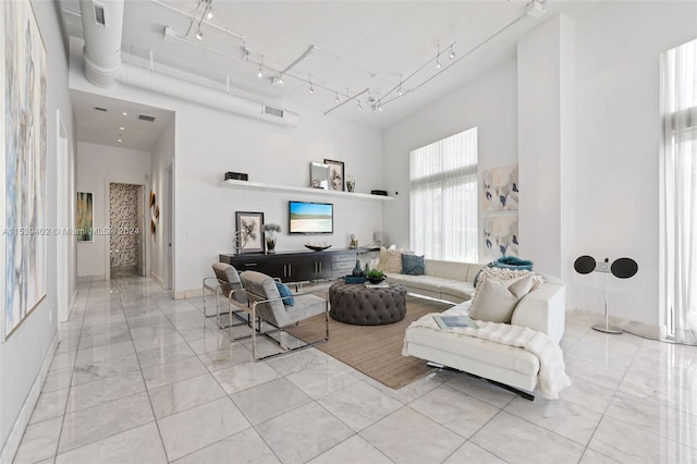 living room featuring track lighting, a towering ceiling, and light tile flooring