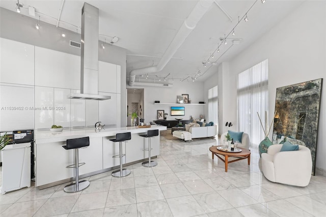 kitchen featuring light tile floors, rail lighting, white cabinetry, and a breakfast bar