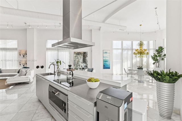 kitchen featuring wall chimney range hood, light tile flooring, black electric cooktop, wall oven, and track lighting