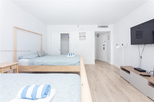 bedroom with light hardwood / wood-style floors and a closet