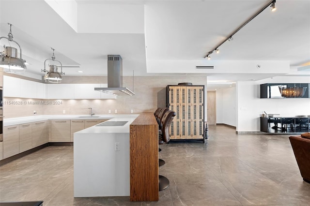 kitchen with island range hood, tile flooring, rail lighting, and sink