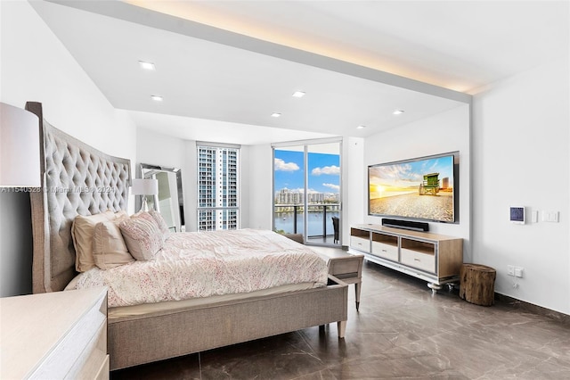 bedroom with access to exterior, a wall of windows, and a water view