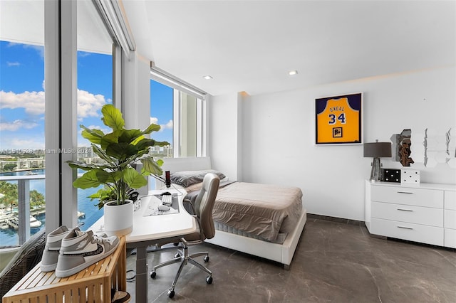 bedroom with multiple windows, a water view, and a wall of windows