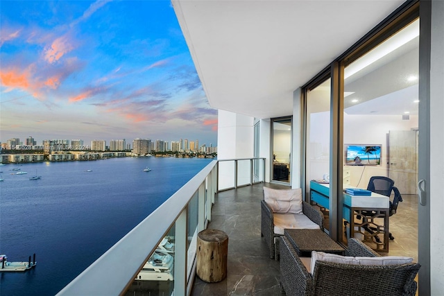 balcony at dusk featuring a water view