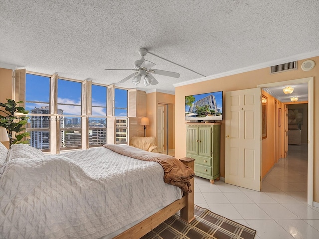 bedroom featuring ornamental molding, a textured ceiling, ceiling fan, and light tile floors