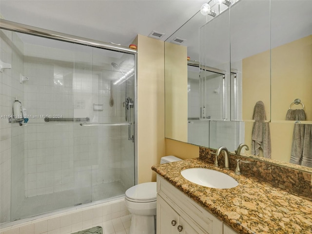 bathroom with tile floors, a shower with shower door, large vanity, and toilet