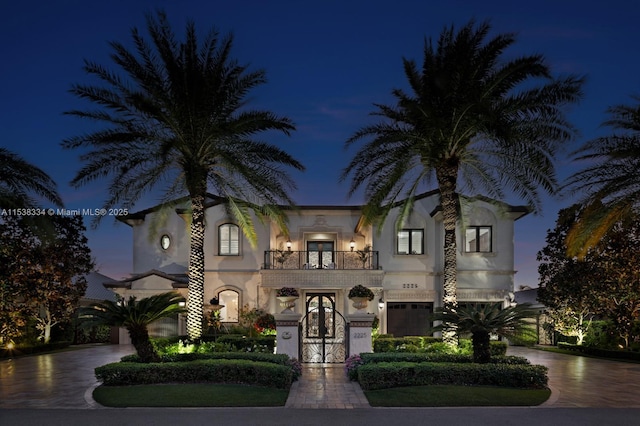 view of front of property featuring a balcony, driveway, stucco siding, and french doors