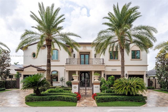 mediterranean / spanish-style home featuring a balcony, french doors, and a garage