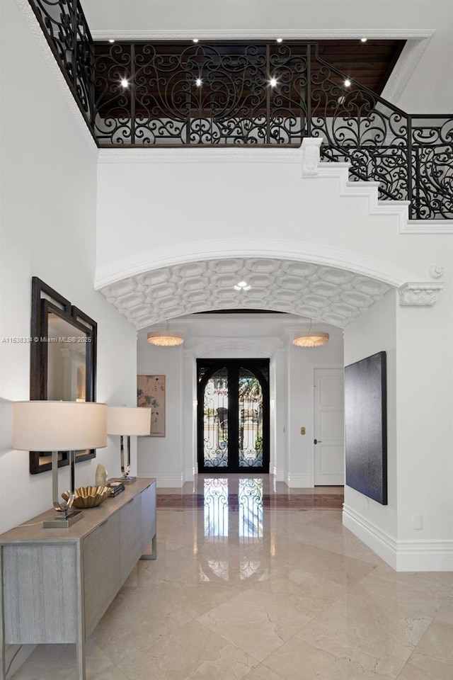 entrance foyer featuring french doors, marble finish floor, a towering ceiling, and baseboards