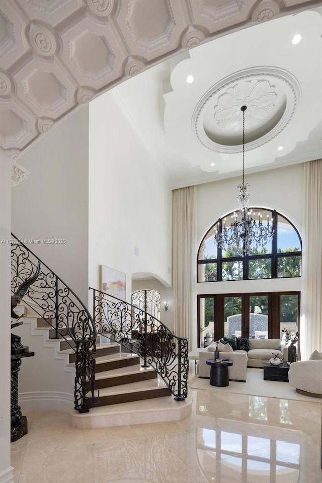 stairway with baseboards, recessed lighting, a raised ceiling, a high ceiling, and a notable chandelier