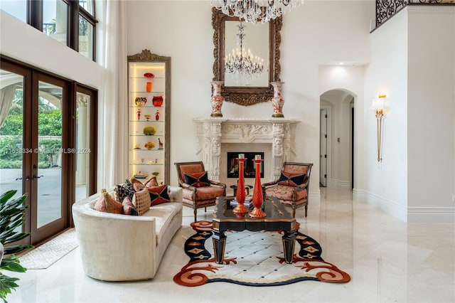 sitting room with a chandelier, french doors, a fireplace, and a high ceiling