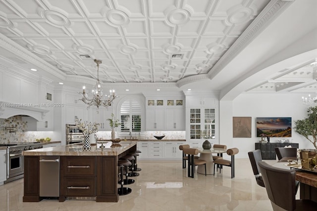 kitchen featuring white cabinetry, tasteful backsplash, high end stainless steel range oven, and a chandelier