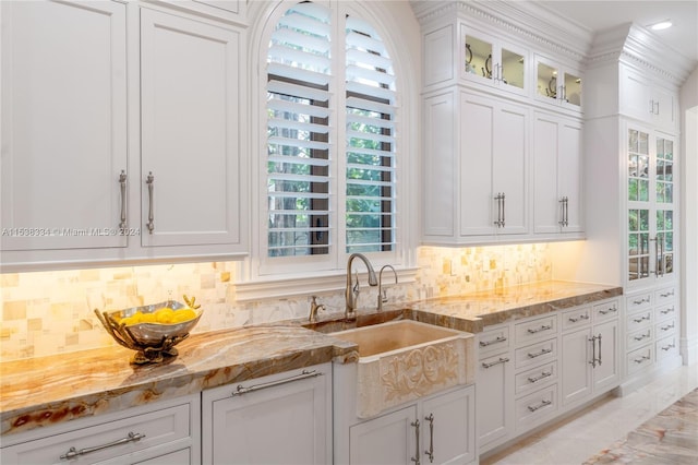 kitchen with light stone counters, white cabinetry, and sink