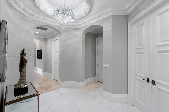 corridor with visible vents, baseboards, ornamental molding, a raised ceiling, and arched walkways