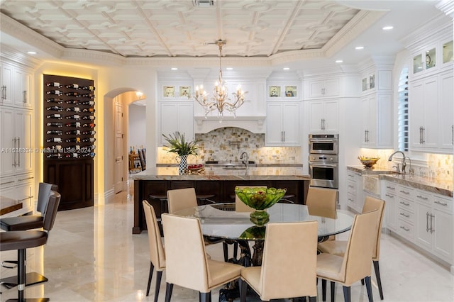 dining space featuring sink, ornamental molding, and an inviting chandelier