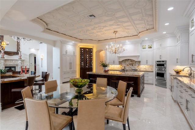 dining area with a notable chandelier, a raised ceiling, sink, and crown molding