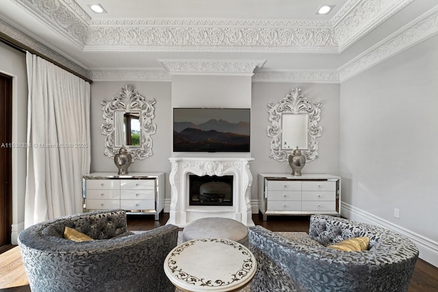 living area featuring crown molding, a tray ceiling, a fireplace, and wood finished floors