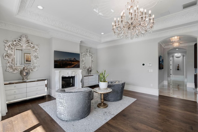 living room with a tray ceiling, arched walkways, visible vents, a fireplace, and wood finished floors