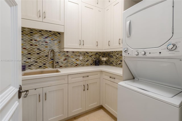 laundry room featuring cabinets, sink, and stacked washer and clothes dryer