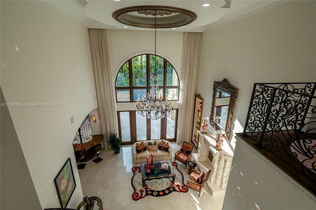 living room with a high ceiling, french doors, a raised ceiling, crown molding, and a chandelier