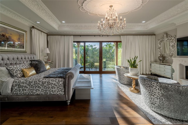 bedroom featuring dark hardwood / wood-style floors, a chandelier, access to outside, a tray ceiling, and ornamental molding