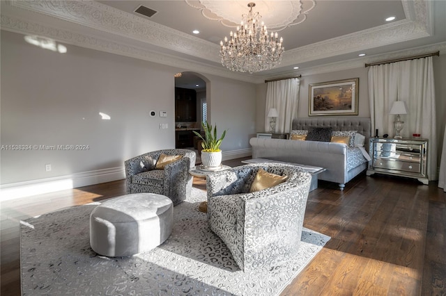 living room with a tray ceiling, hardwood / wood-style floors, an inviting chandelier, and ornamental molding