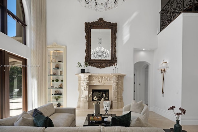 living room with baseboards, a towering ceiling, a fireplace, arched walkways, and an inviting chandelier