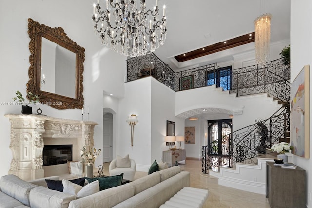 living room with stairs, a notable chandelier, a high end fireplace, baseboards, and arched walkways