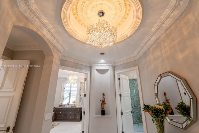 hallway featuring a raised ceiling, crown molding, and a notable chandelier