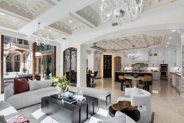 living area featuring coffered ceiling, recessed lighting, ornamental molding, a chandelier, and arched walkways