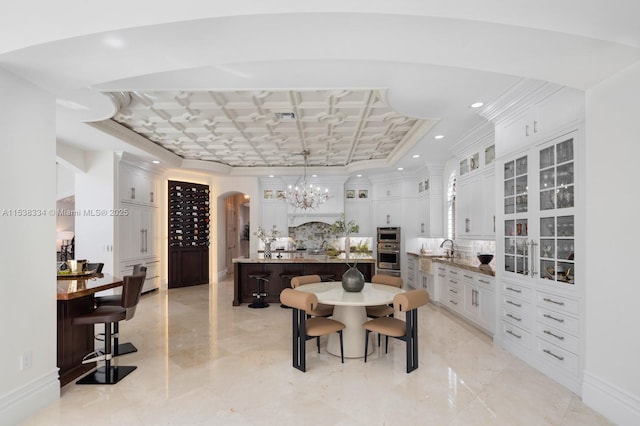 dining area with a chandelier, baseboards, recessed lighting, arched walkways, and coffered ceiling