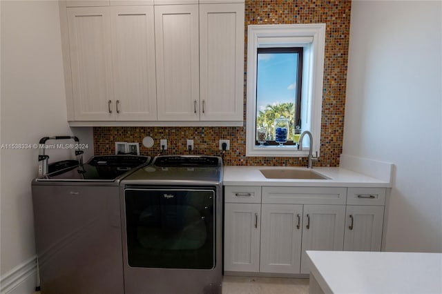 laundry area with washing machine and clothes dryer, cabinets, and sink