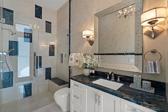 bathroom with an inviting chandelier, toilet, vanity, and a stall shower
