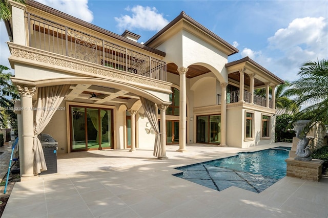 rear view of house featuring ceiling fan, a balcony, and a patio