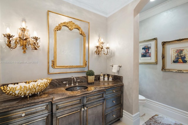 half bath with vanity, toilet, ornamental molding, baseboards, and marble finish floor