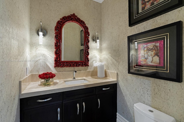 bathroom with wallpapered walls, toilet, and vanity