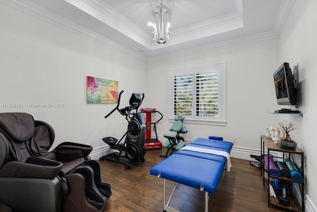 exercise room with a notable chandelier, crown molding, a raised ceiling, wood finished floors, and baseboards