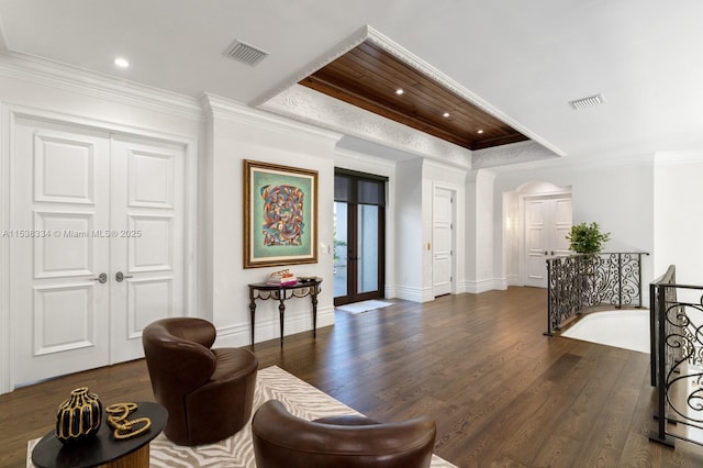 living area with dark wood-style flooring, ornamental molding, baseboards, and visible vents