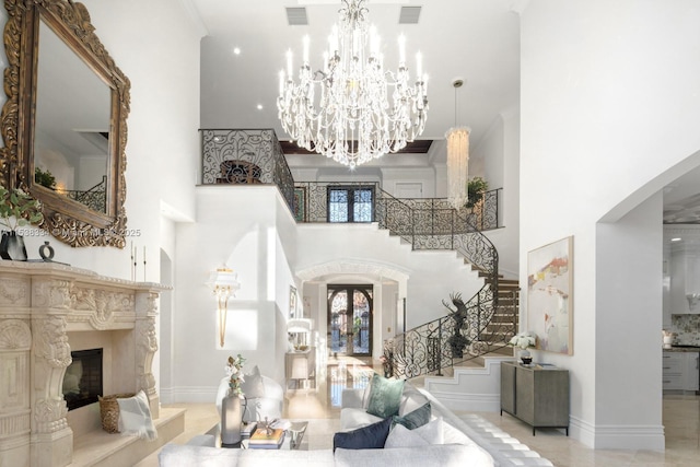 entryway with stairway, a high ceiling, visible vents, a notable chandelier, and a fireplace