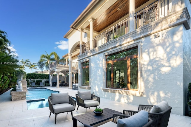 view of patio / terrace with a balcony, an outdoor living space, and a fenced in pool
