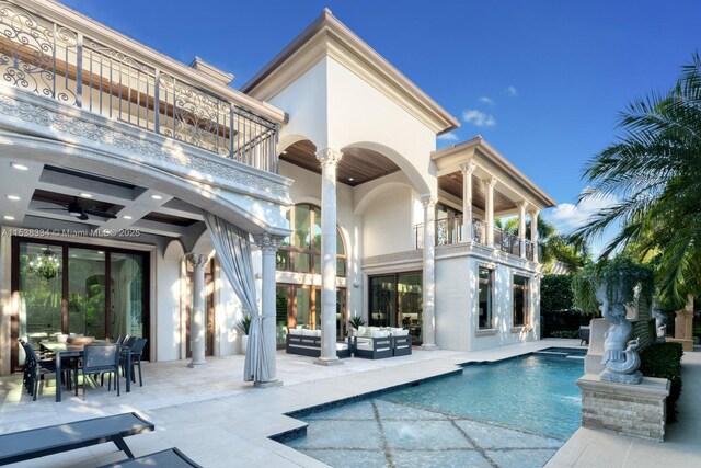 rear view of property featuring an outdoor hangout area, a balcony, stucco siding, and a patio area