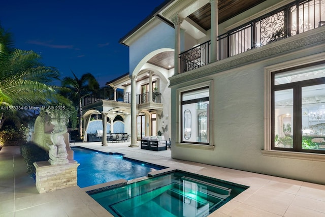 pool at twilight with an in ground hot tub and a patio area